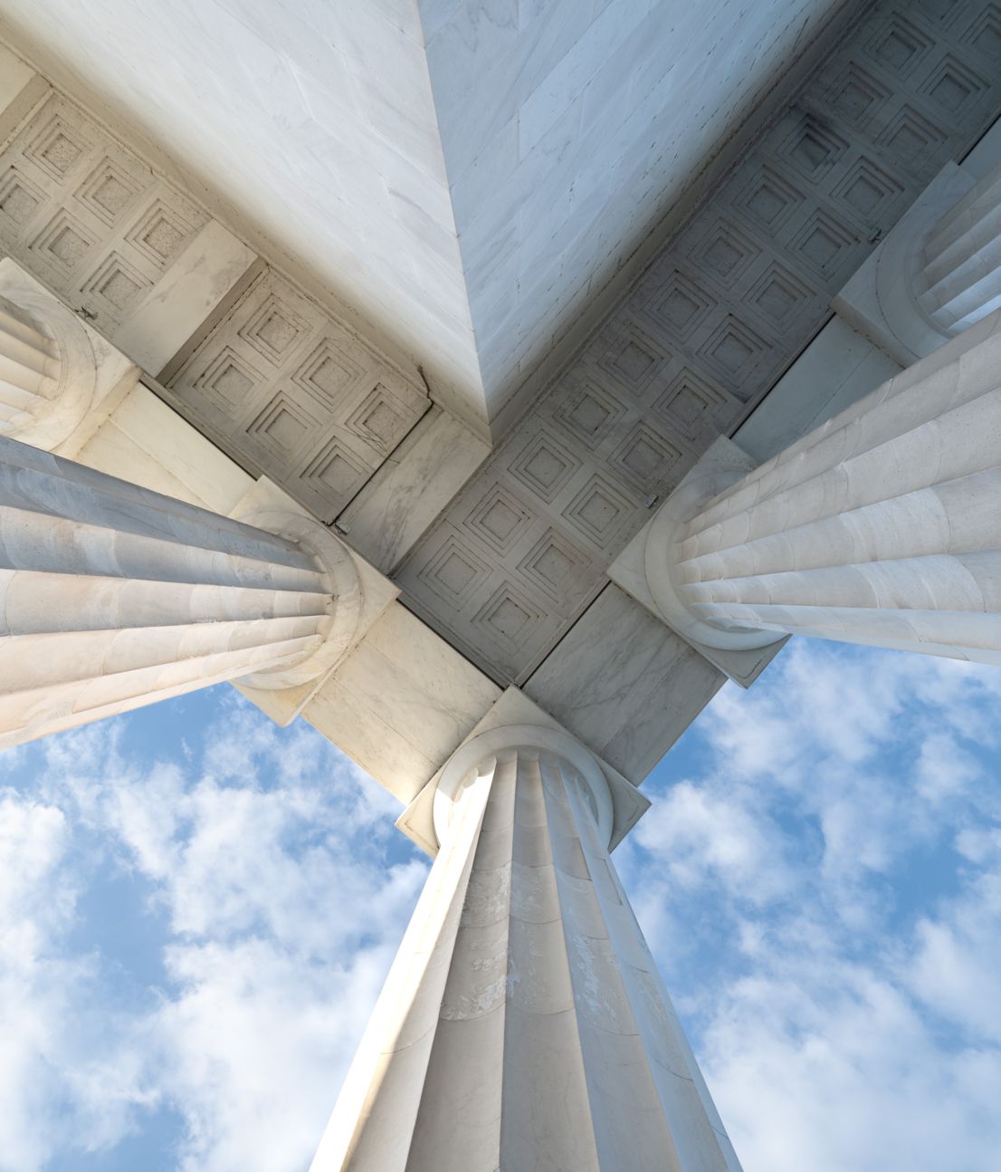 Marble columns seen from below against a blue sky